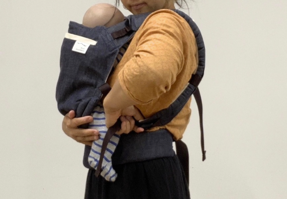 バックルタイプの抱っこ紐を親子に合わせて調整している様子